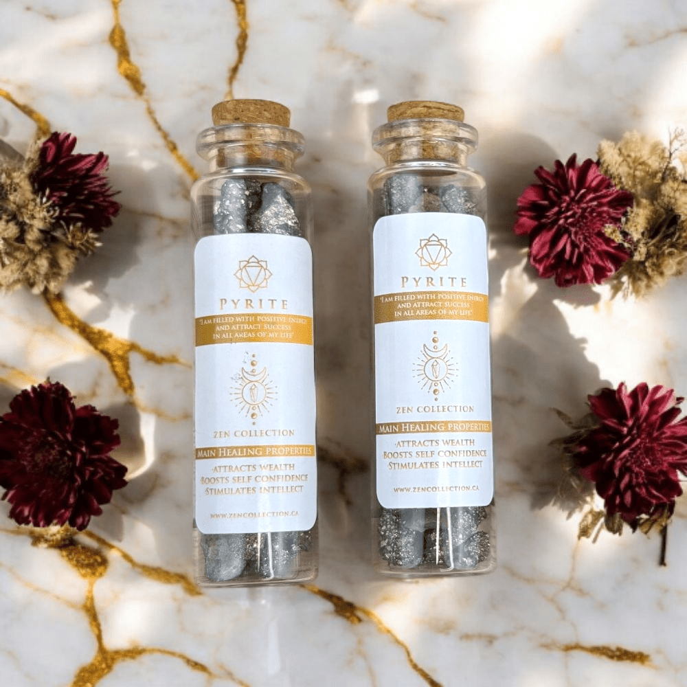 Two glass bottles of pyrite crystals with cork lids on a marble surface with dried flowers