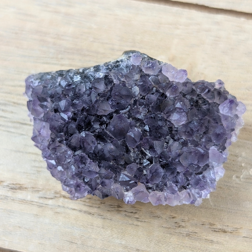 Ethically sourced Rainbow Amethyst cluster on a natural surface.