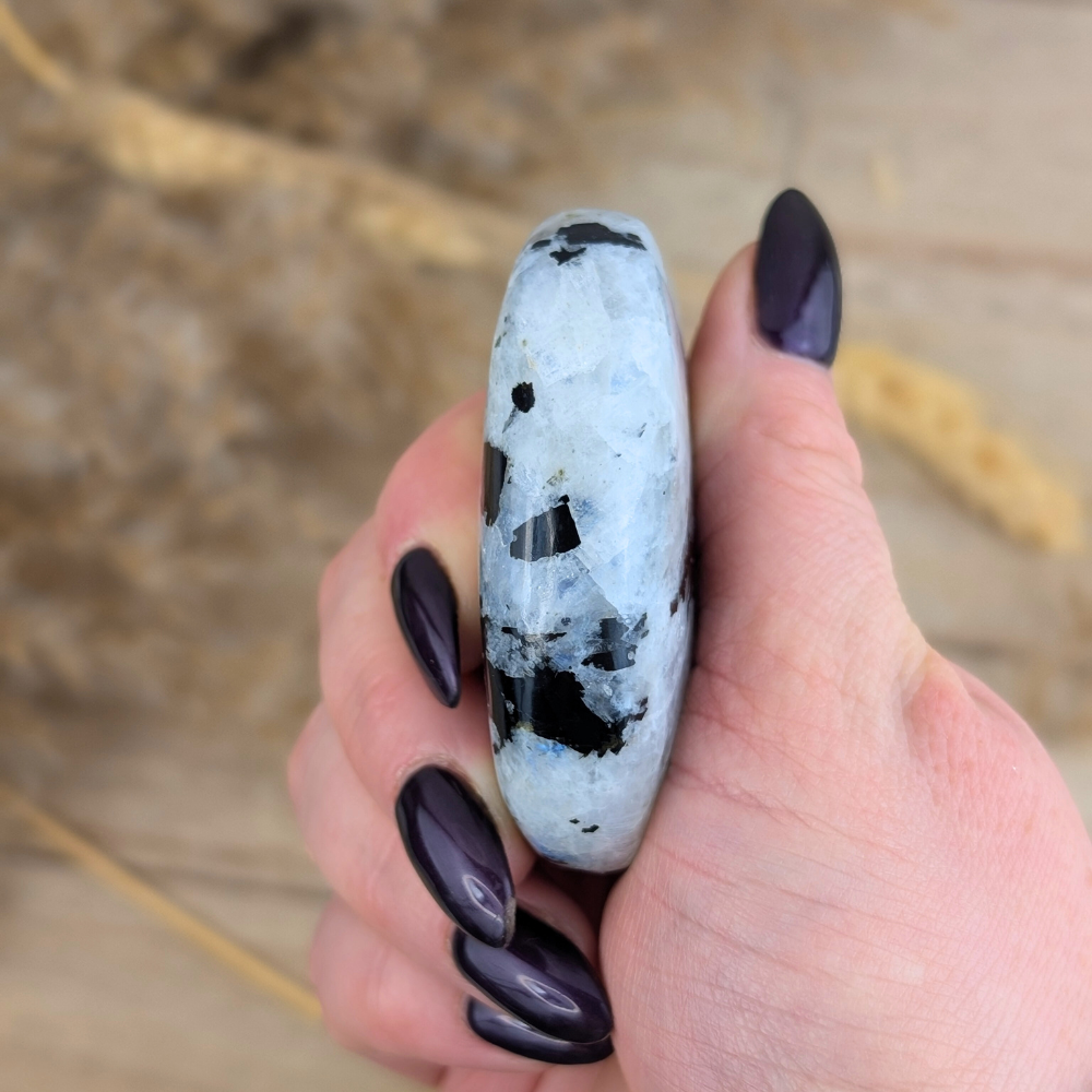 Side view of Rainbow Moonstone Palm Stone under natural light