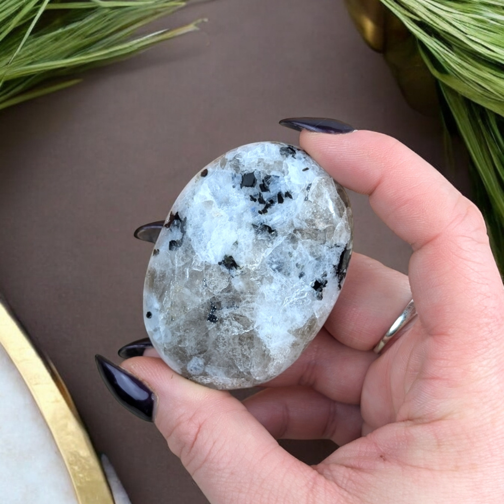 Close-up of Rainbow Moonstone Crystal Palm Stone showcasing inclusions.