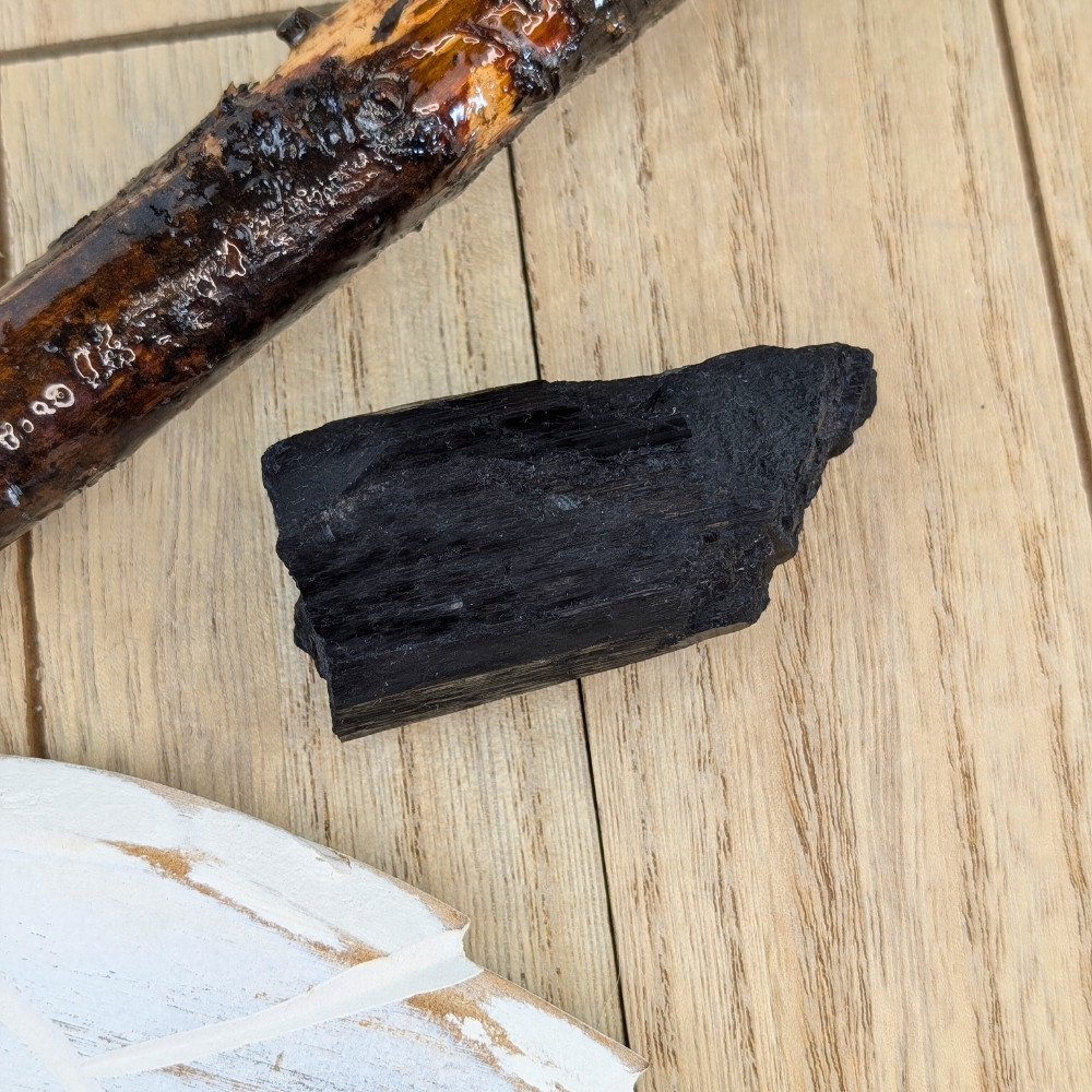 Black Tourmaline Crystal for Grounding and Protection - A raw Black Tourmaline crystal placed against a neutral background, emphasizing its protective and healing properties.