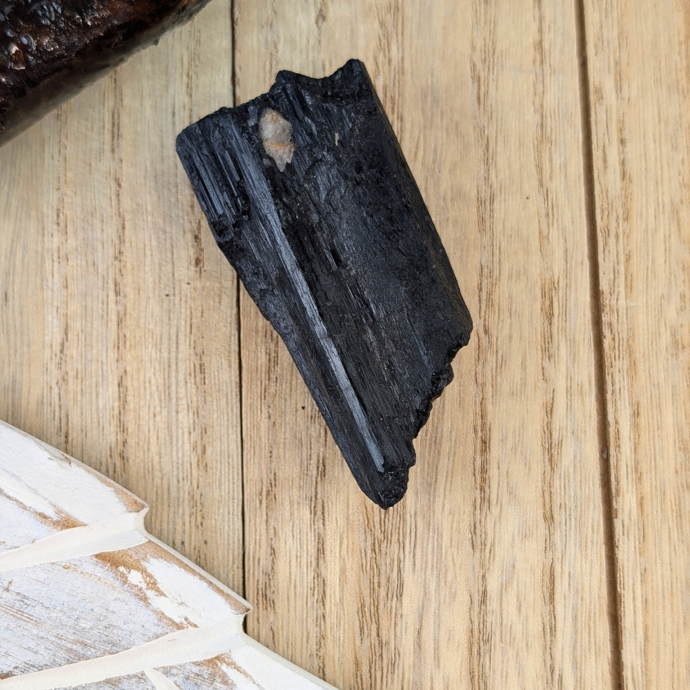 Raw Black Tourmaline Protection Stone - A handheld Black Tourmaline crystal, demonstrating its size and natural form as a grounding and protective stone.