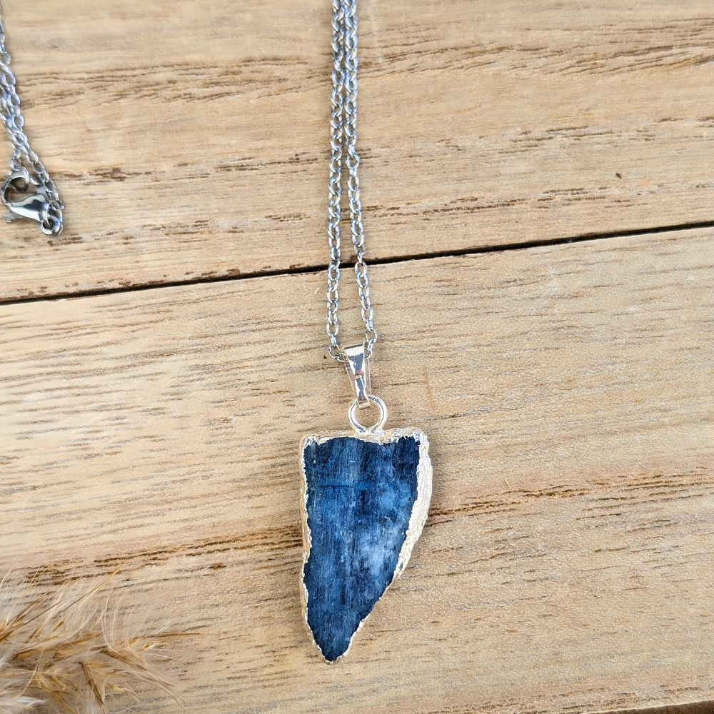 Natural Raw Kyanite crystal necklace displayed on rustic wood.