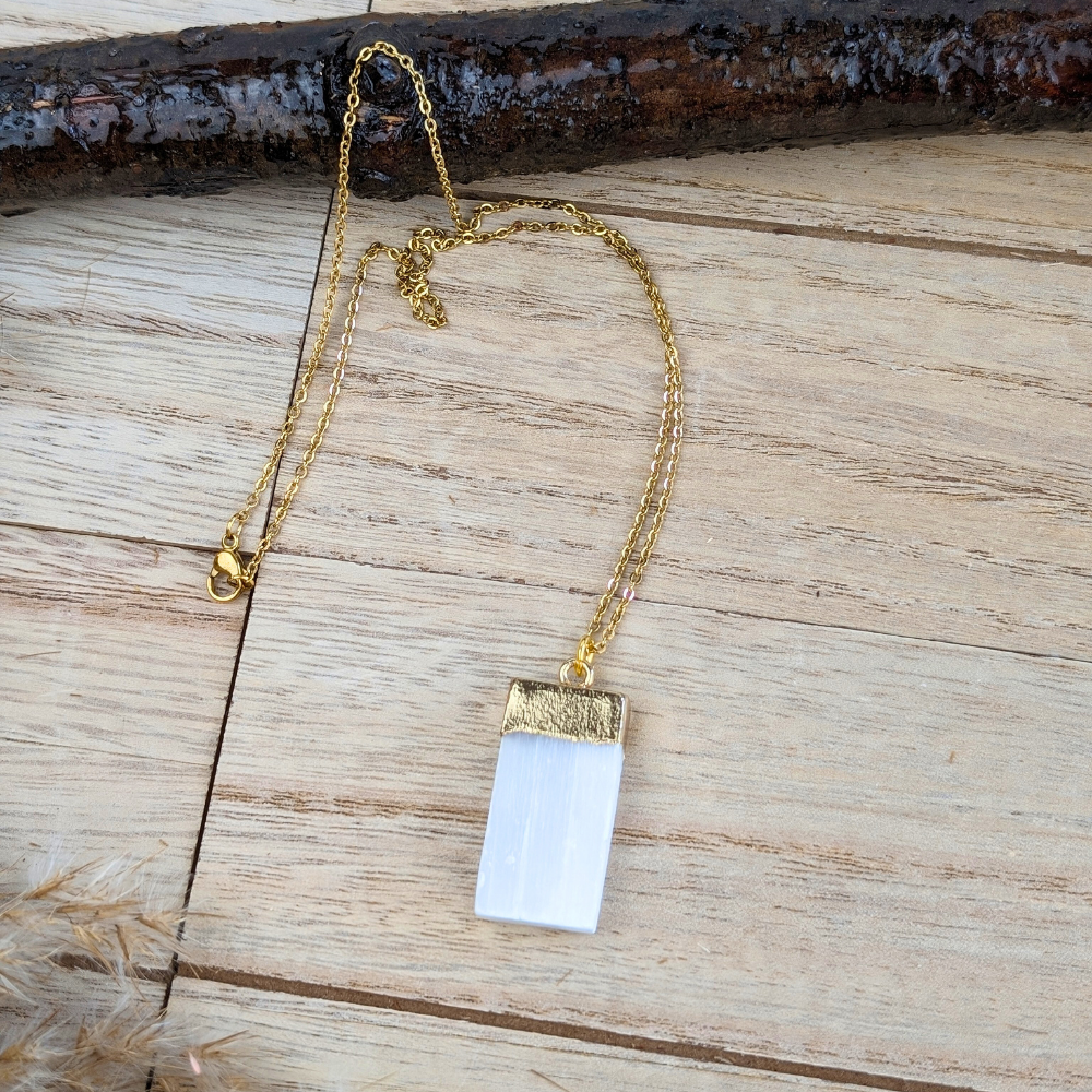 Adjustable gold-tone selenite necklace on wood background