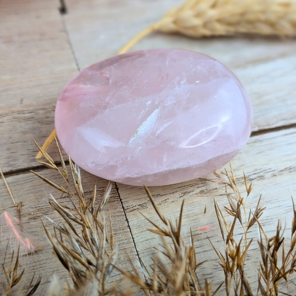 Polished Rose Quartz Crystal Palm Stone lying flat.