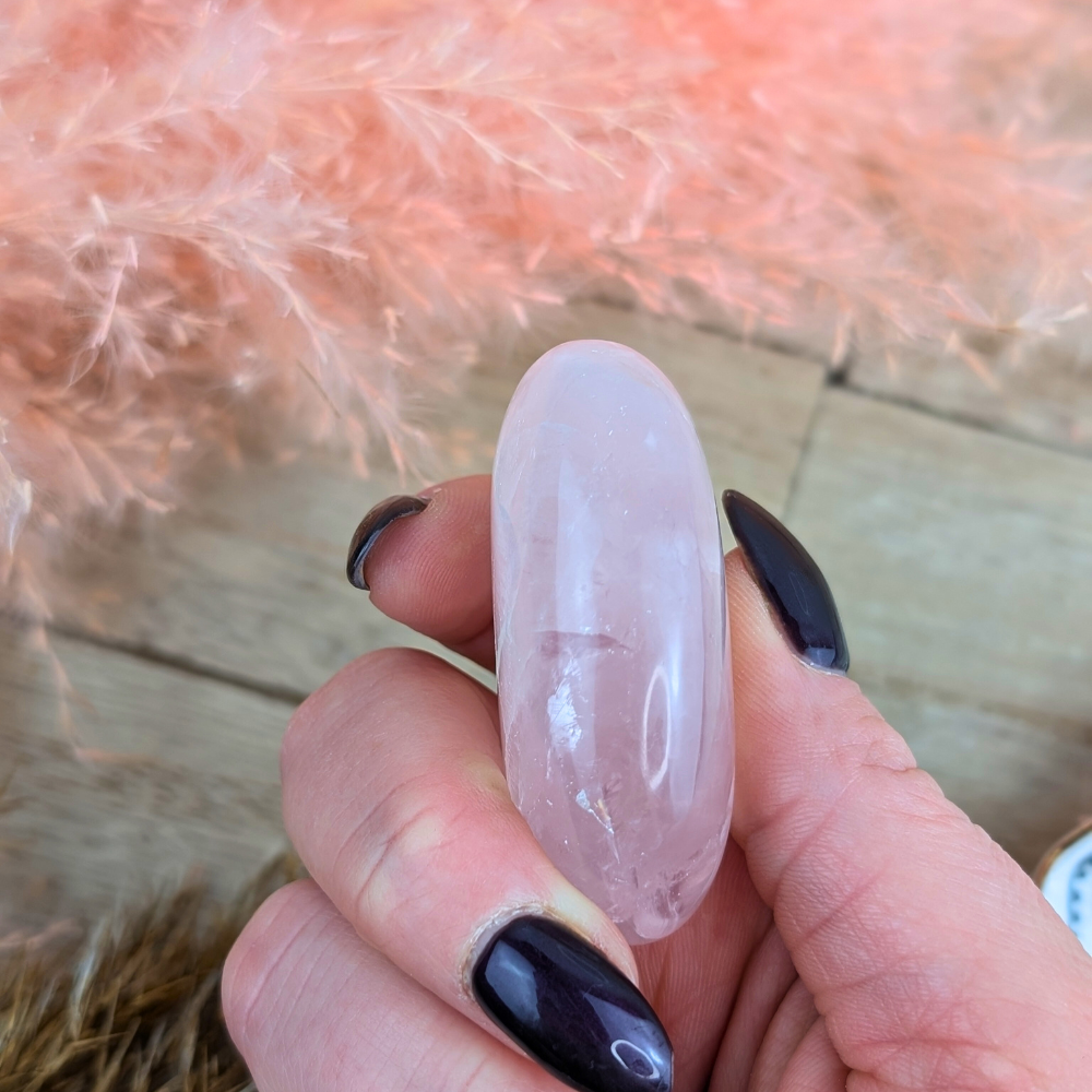 Hand holding Rose Quartz Palm Stone for meditation and self-love