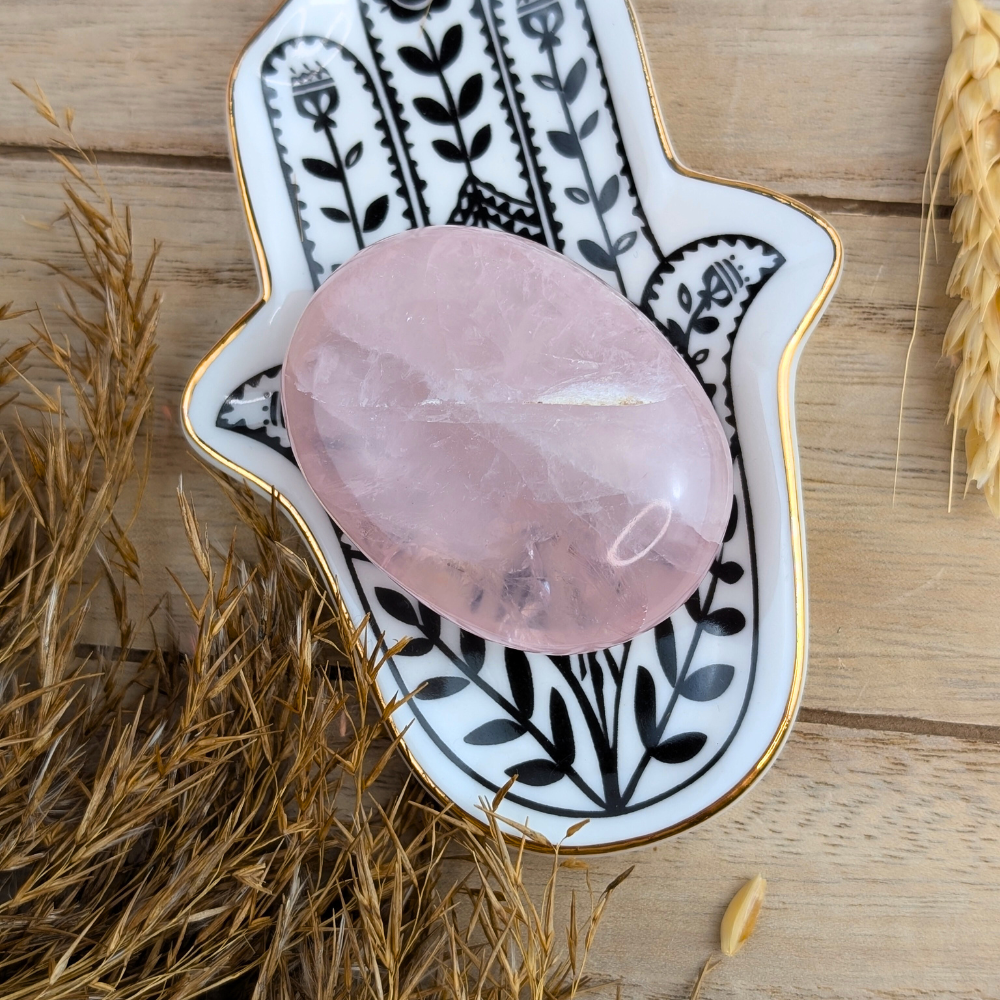 Rose Quartz Palm Stone displayed with other crystals like clear quartz.