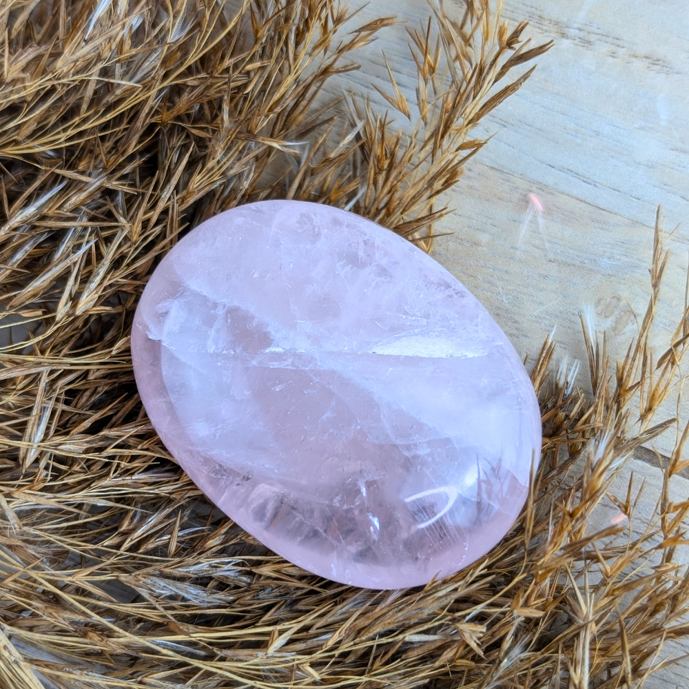 Oval-shaped Rose Quartz Palm Stone on an altar setting