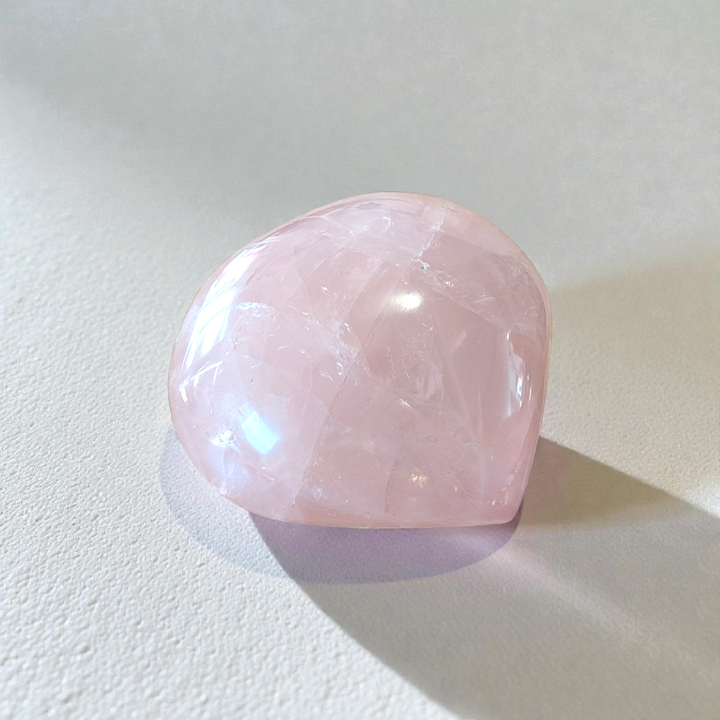 Soft pink rose quartz crystal heart for emotional healing and mindfulness.