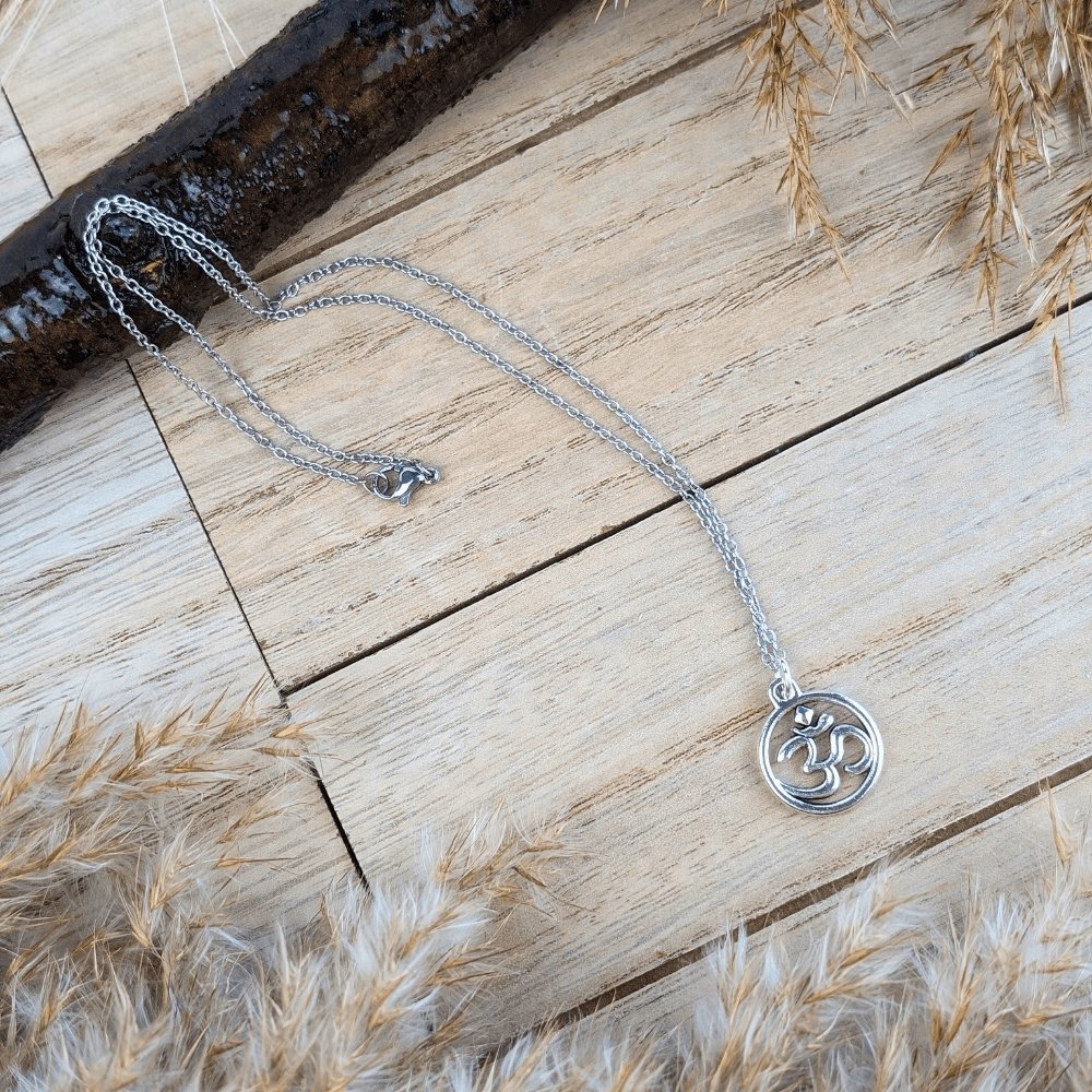 Elegant silver-tone Sacred Om Necklace displayed on a natural wooden surface