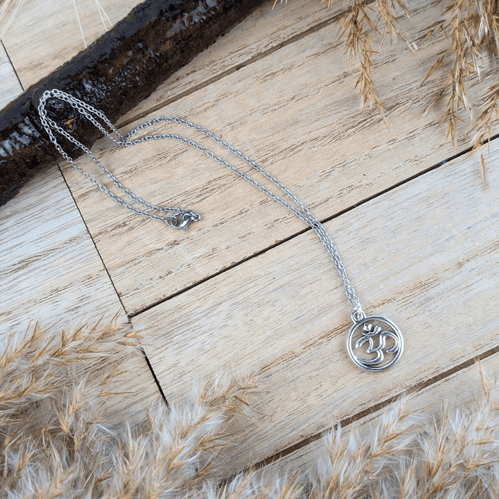 Elegant silver-tone Sacred Om Necklace displayed on a natural wooden surface