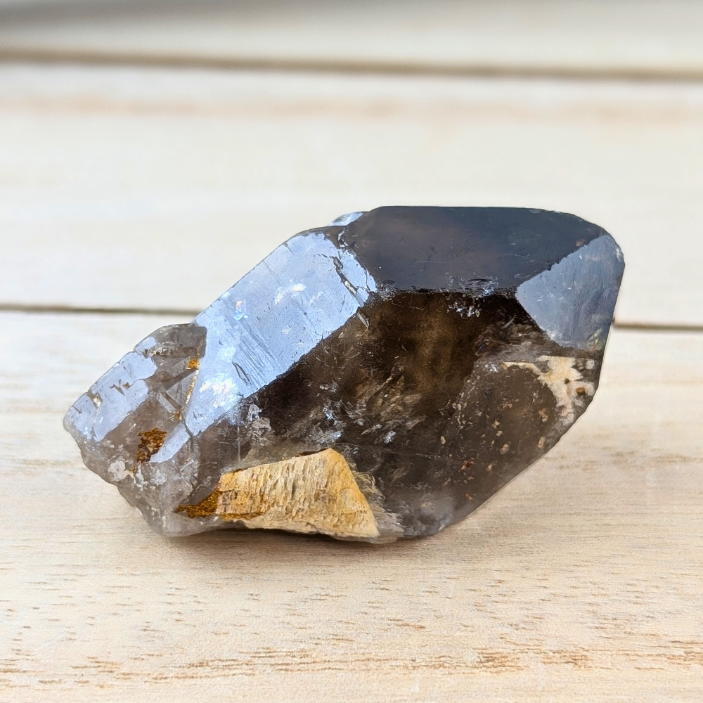 Smoky Quartz point crystal on a wooden surface