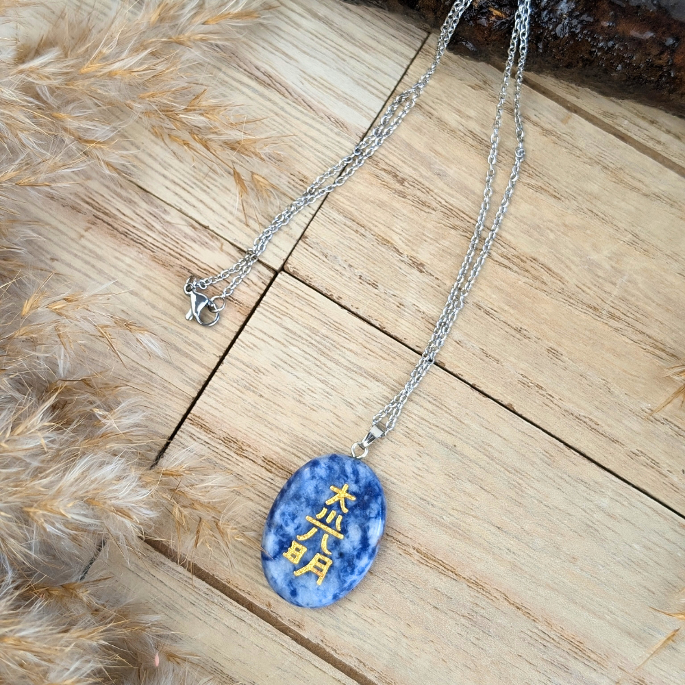 Close-up of the Sodalite Reiki Necklace showing its deep blue stone and golden engraving