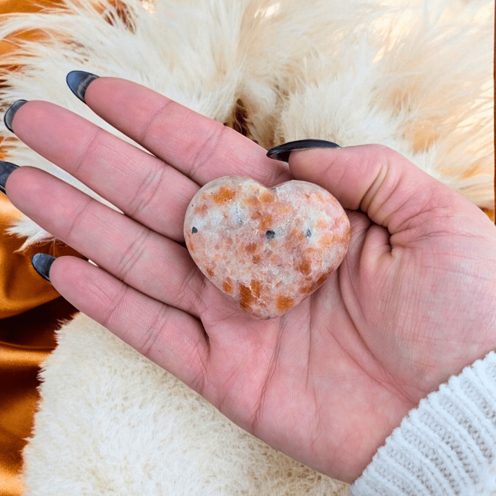 Hand holding a Sunstone Crystal Heart for meditation.