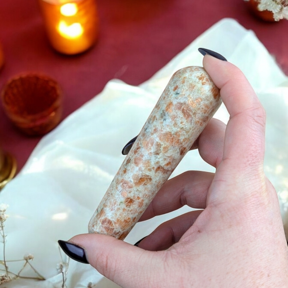 Hand holding the Sunstone Crystal Wand for energy work