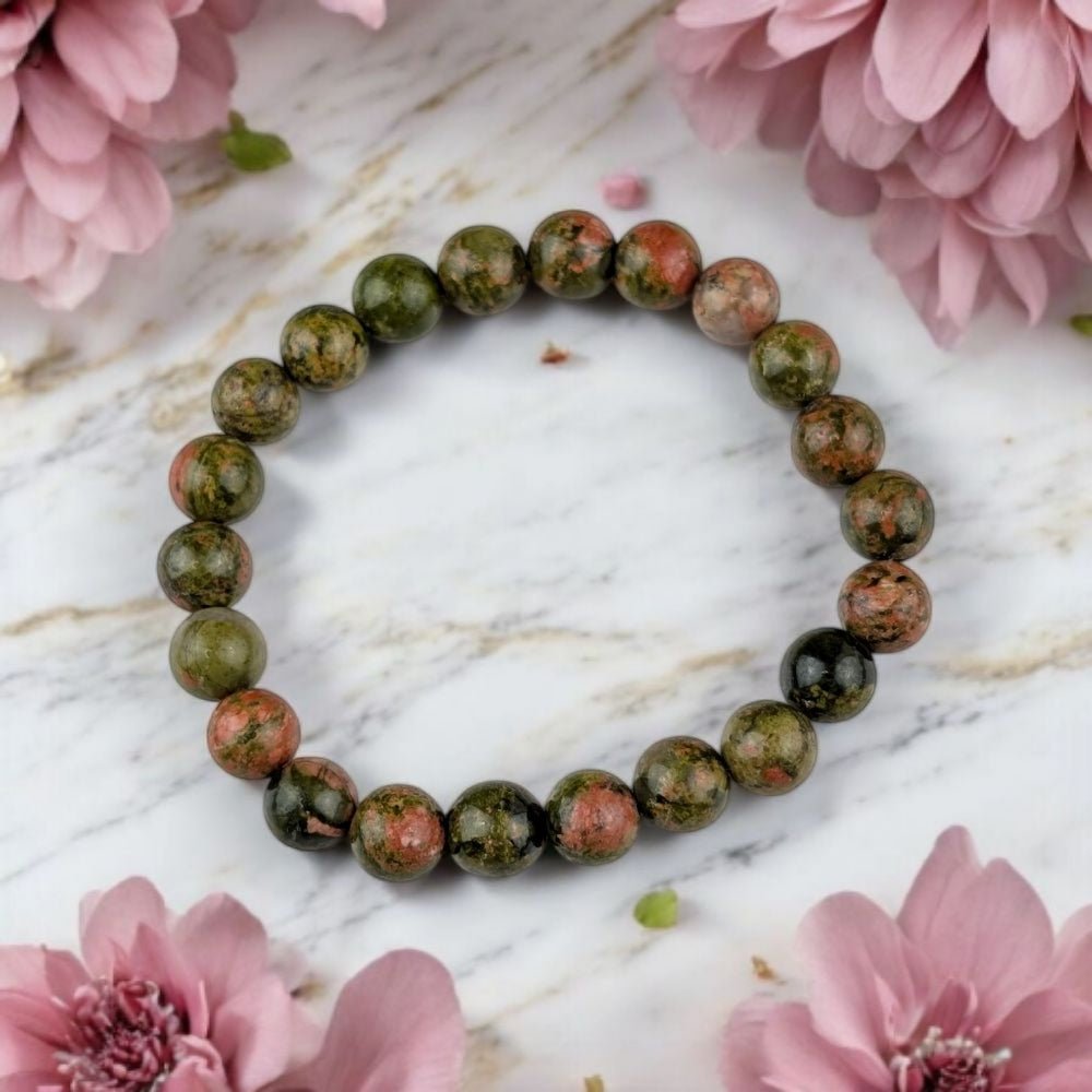 Fertility Crystal for Pregnancy Support beaded bracelet on a marble surface with pink flowers