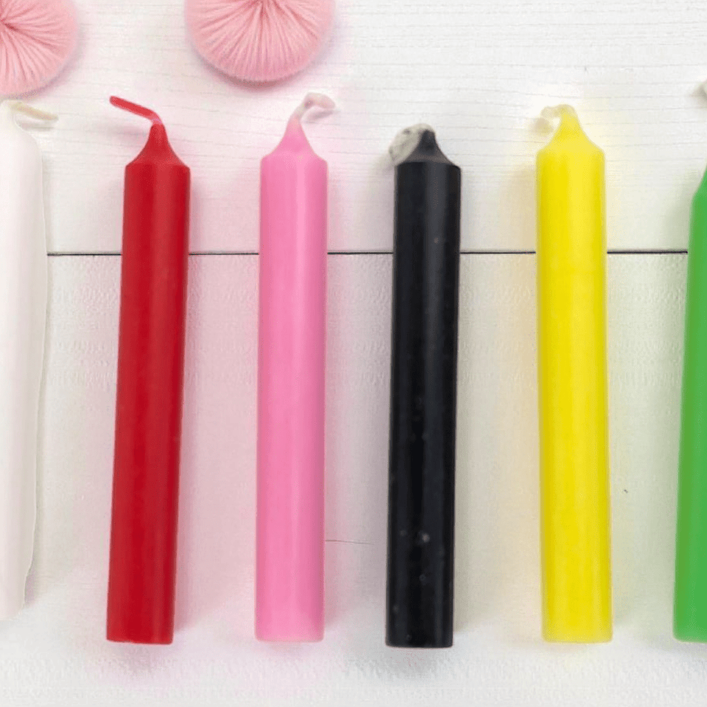 Five colorful spell candles on a white surface with decorative elements. Available at Zen Collection crystal store in Barrie 