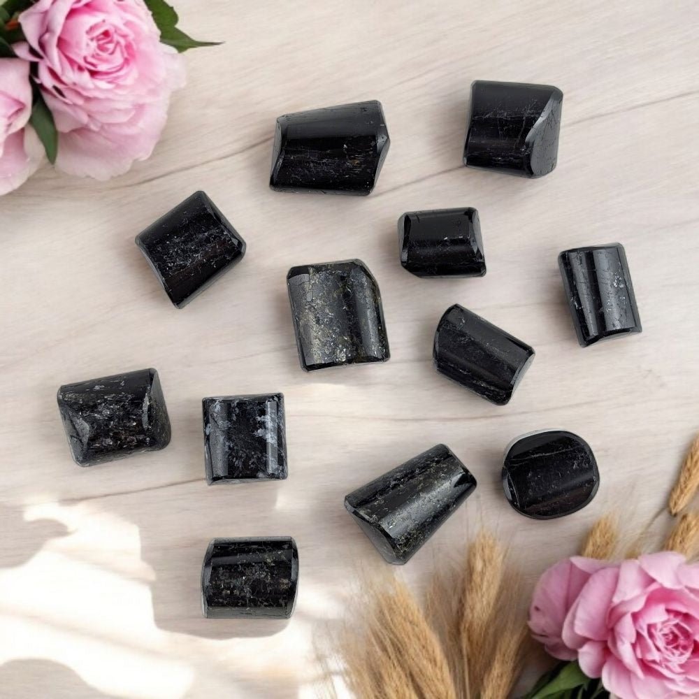 Black Tourmaline crystals a light wooden surface with pink roses and wheat stalks