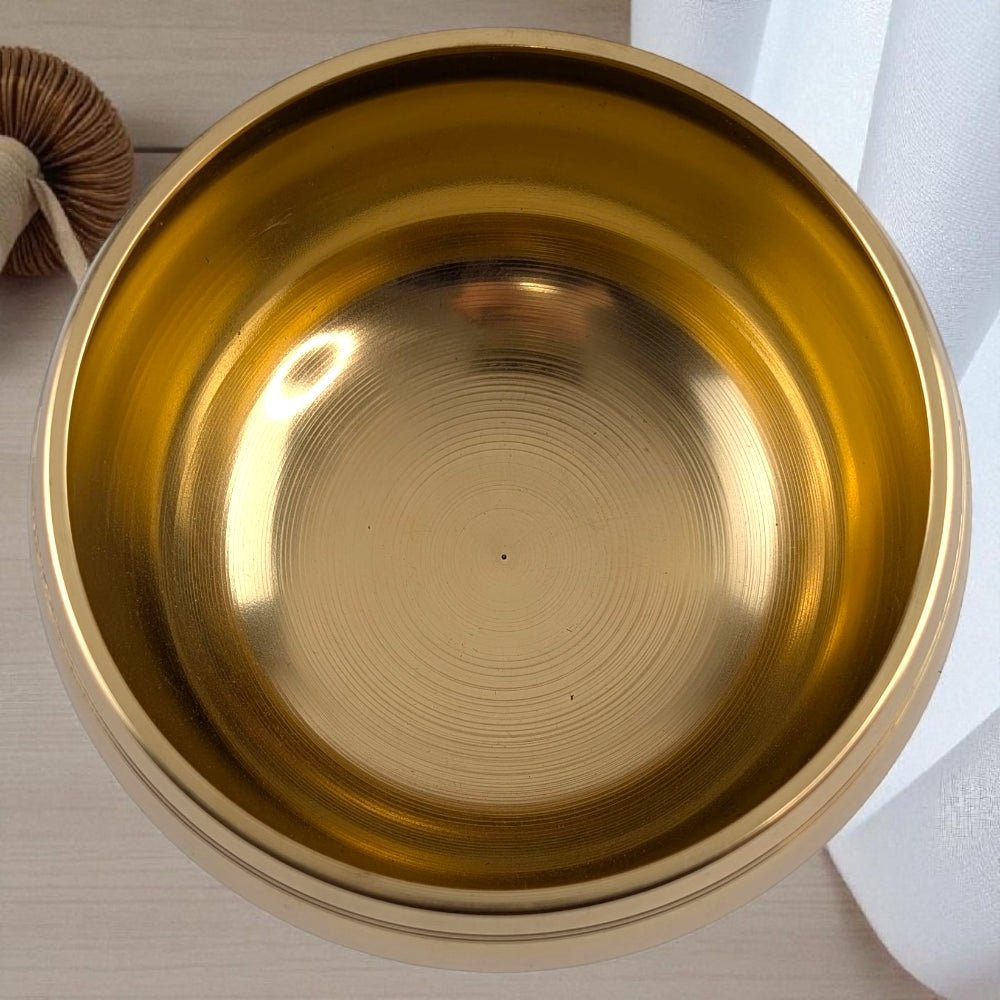 Gold singing bowl with wooden striker on a neutral background available at Zen Collection Crystal Store in Barrie