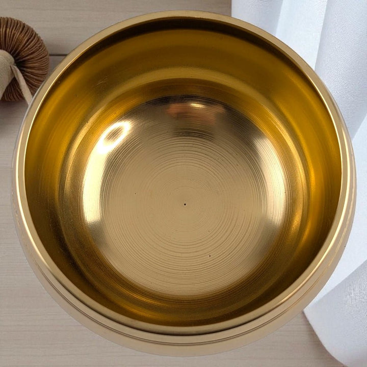 Gold singing bowl with wooden striker on a neutral background available at Zen Collection Crystal Store in Barrie