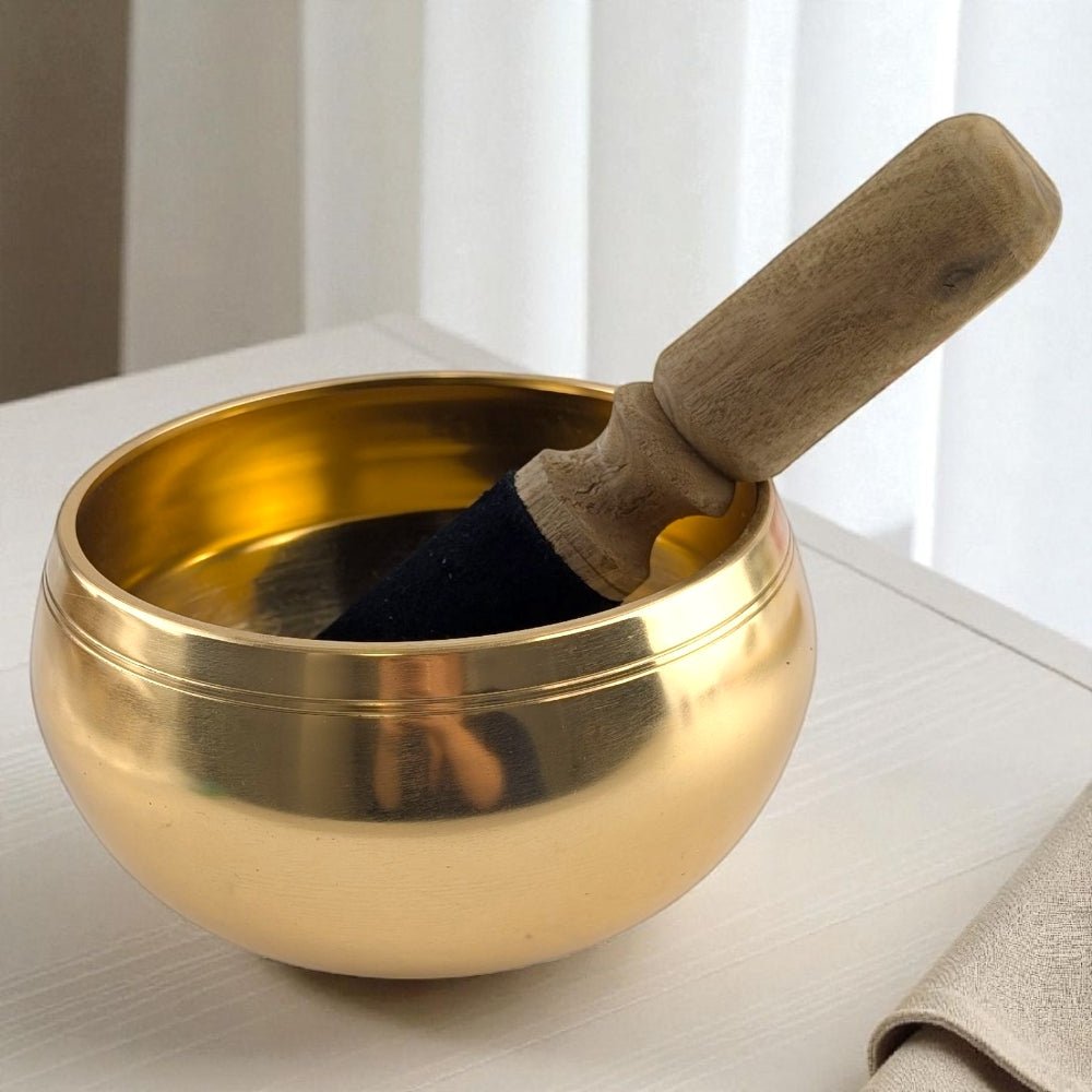 Gold singing bowl with wooden striker on a neutral background available at Zen Collection Crystal Store in Barrie