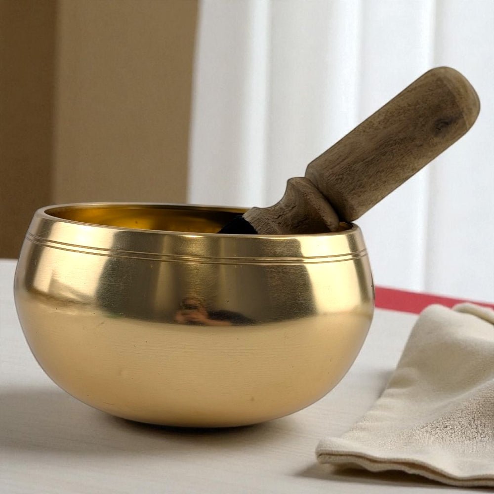 Gold singing bowl with wooden striker on a neutral background available at Zen Collection Crystal Store in Barrie
