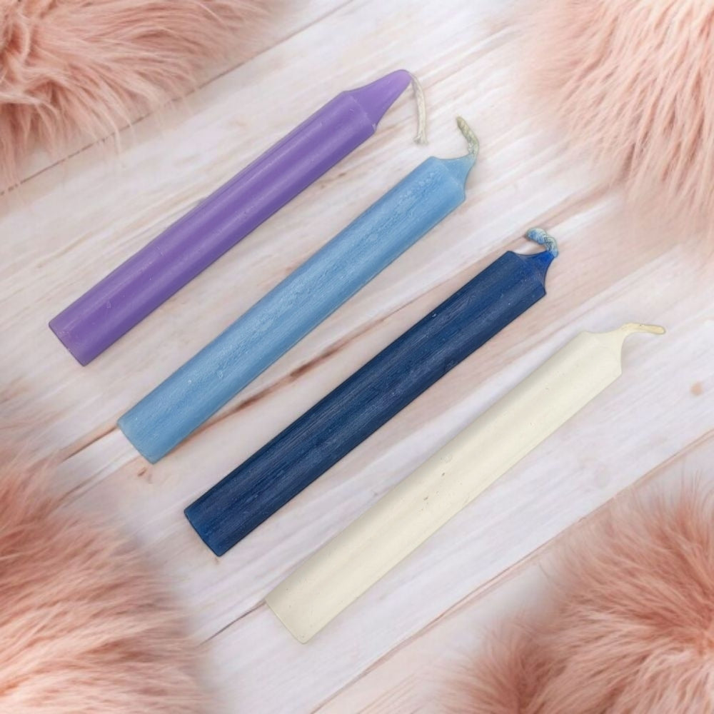 Four colored candles on a wooden surface with a fluffy pink background