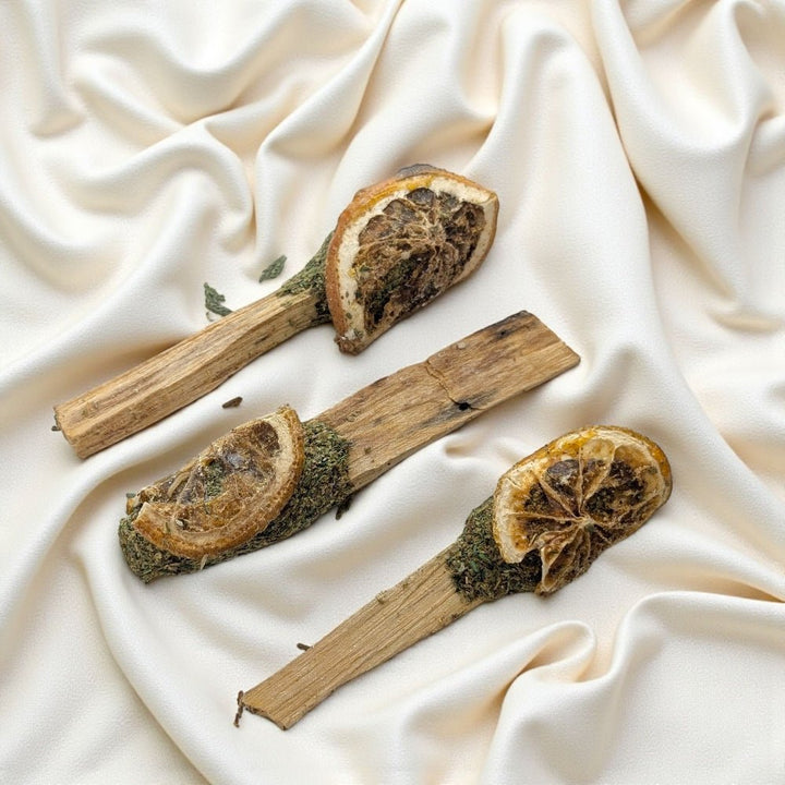 Three dried orange slices on palo santo  sticks with cedar against a beige fabric background available at zen collection metaphysical store in barrie