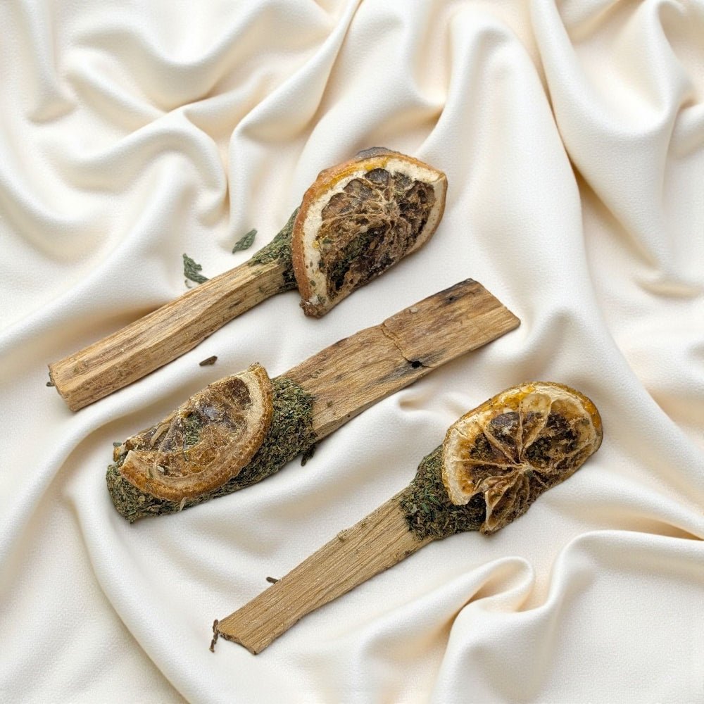 Three dried orange slices on palo santo  sticks with cedar against a beige fabric background available at zen collection metaphysical store in barrie