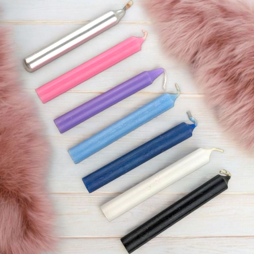 Set of colorful candles to support those who are sensitive to energy on a wooden surface with pink fur on the sides.