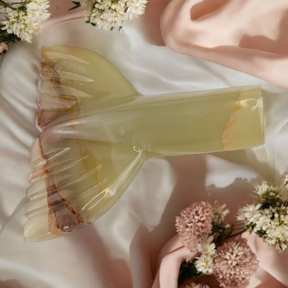 carved banded calcite crystal with floral arrangement on a soft fabric background