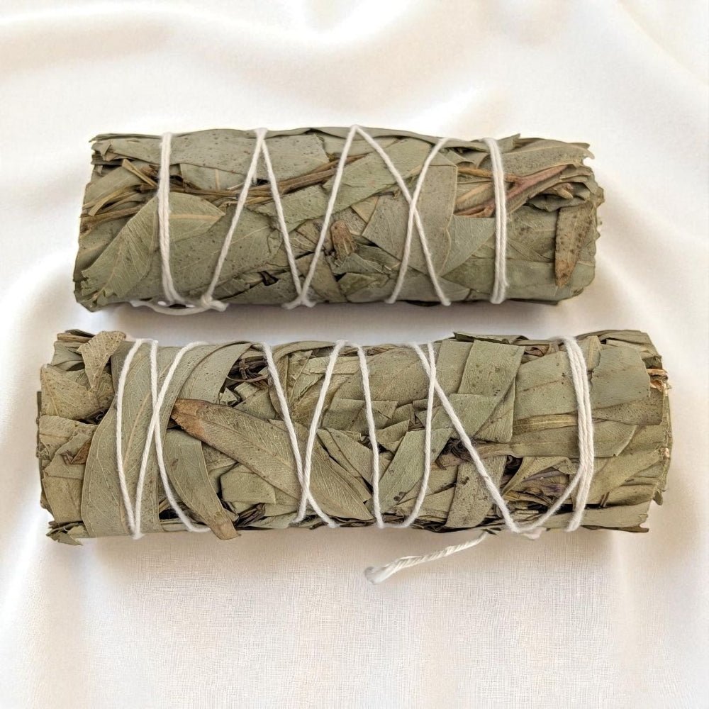 Two bundles of eucalyptus tied with white string on a light background available at crystal store in Barrie