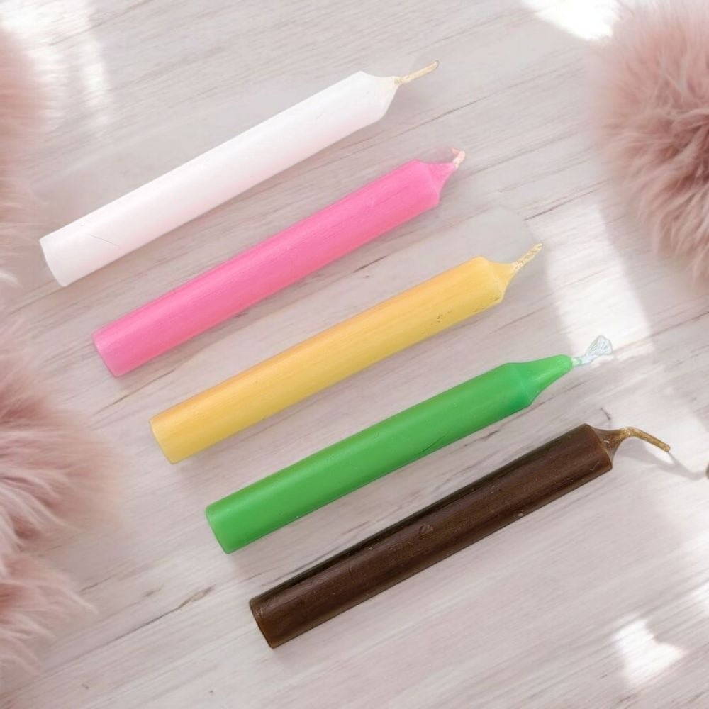 Five colorful fertility blessing candle set with five chime candles on a light wooden surface with fluffy pink objects around.