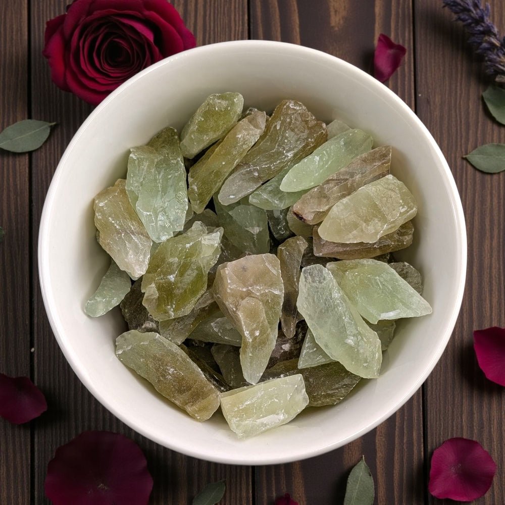 Heart Chakra Crystals - White bowl filled with green crystals on a wooden surface with flowers and leaves. Available at Zen Collection crystal healing store in barrie