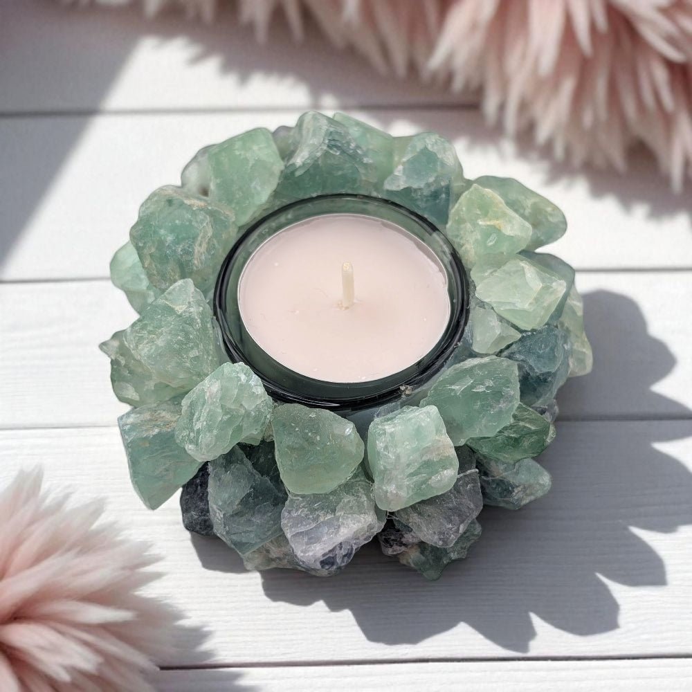 Candle holder made of green fluorite crystals on a light wooden surface
