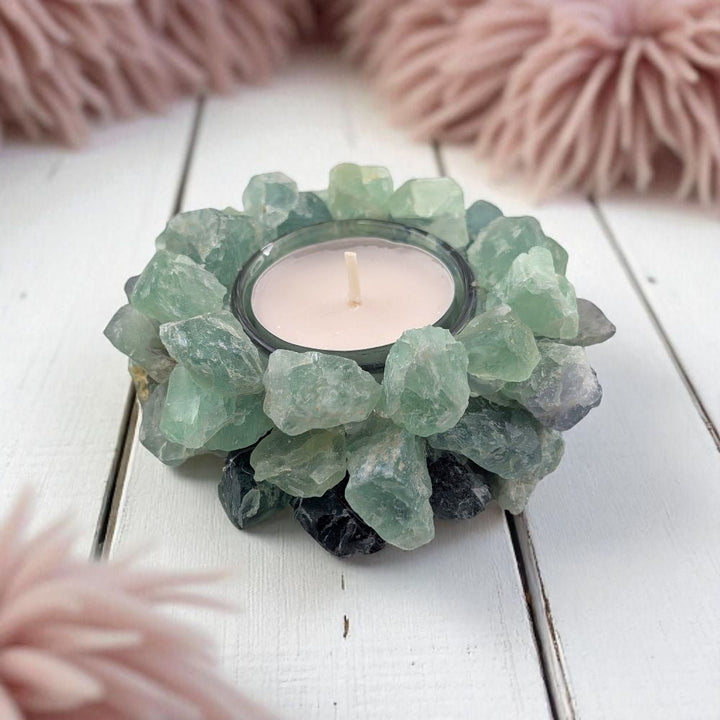 Candle holder made of raw green fluorite crystals on a white wooden surface