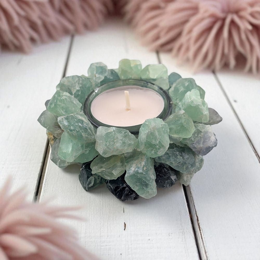 Candle holder made of raw green fluorite crystals on a white wooden surface
