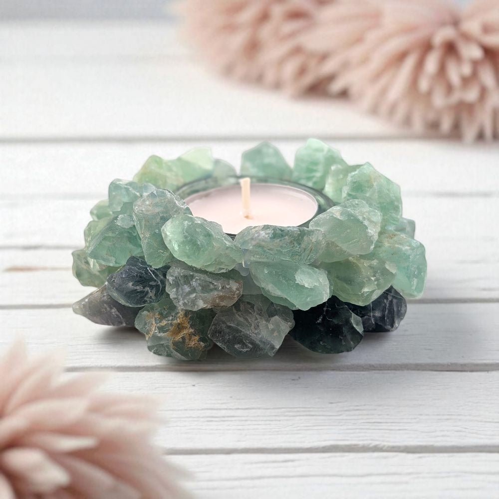 Tealight candle holder made of green fluorite crystals on a light wooden surface