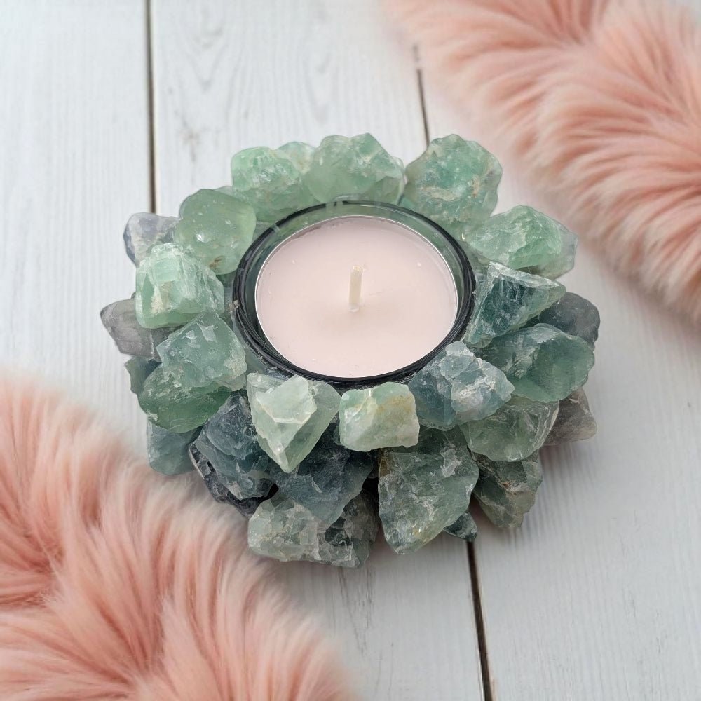 Candle holder made of green fluorite crystals on a white wooden surface