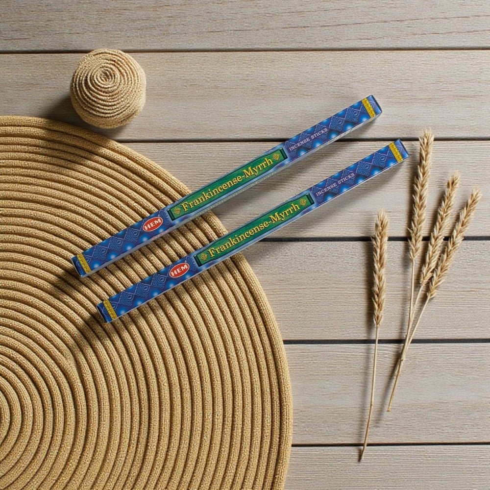 Two packages of Frankincense Myrrh incense on a wooden surface with a woven mat and wheat stalks. available at a crystal store near me