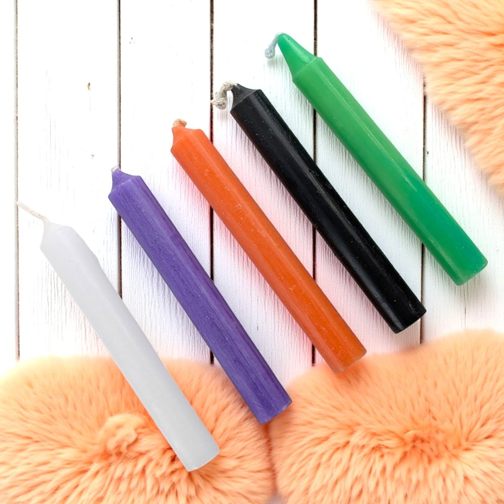 Colorful candles on a wooden surface with a fluffy orange blanket underneath available at metaphysical stores barrie