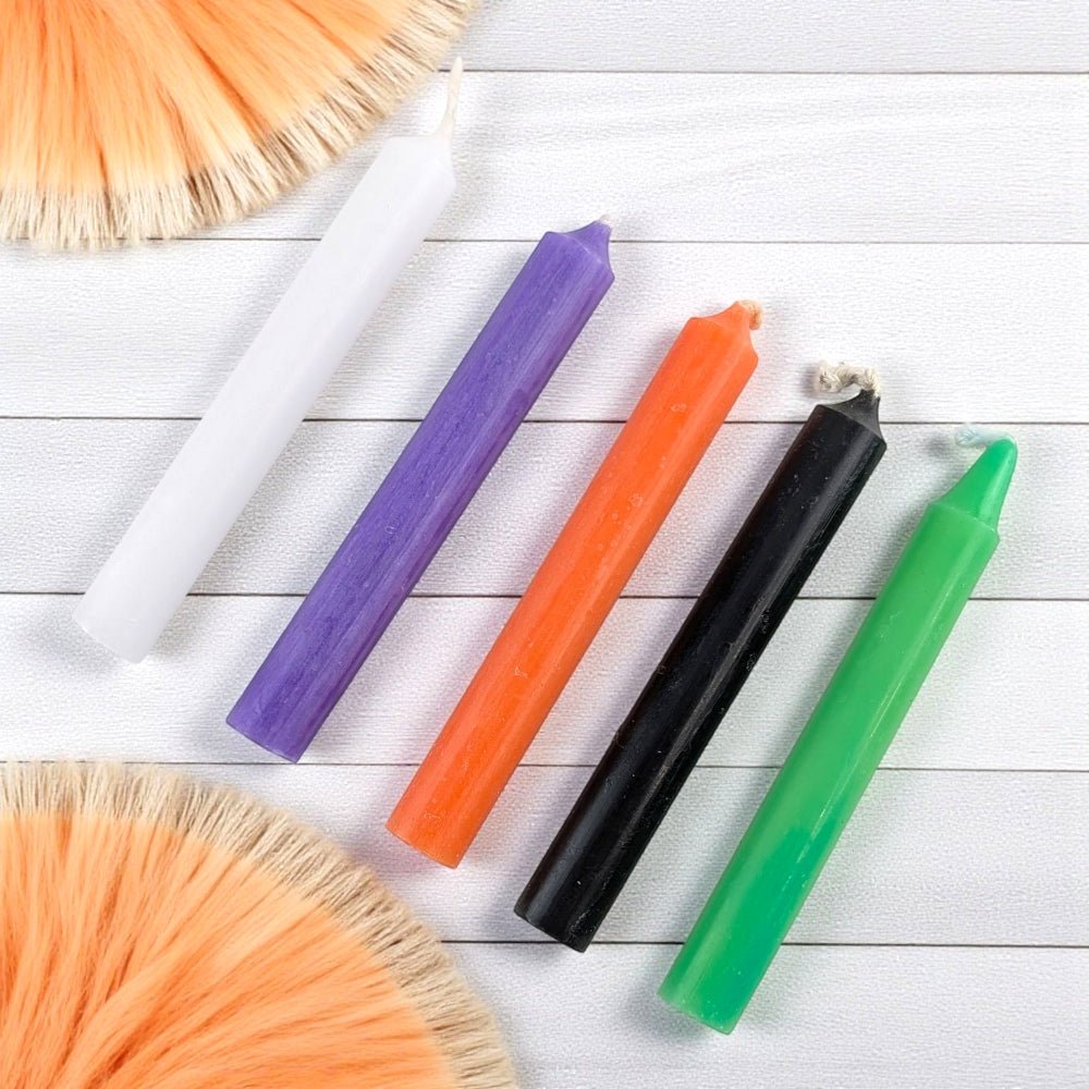 Colorful candles on a white wooden surface with orange straw-like objects. available at barrie crystal stores, zen collection
