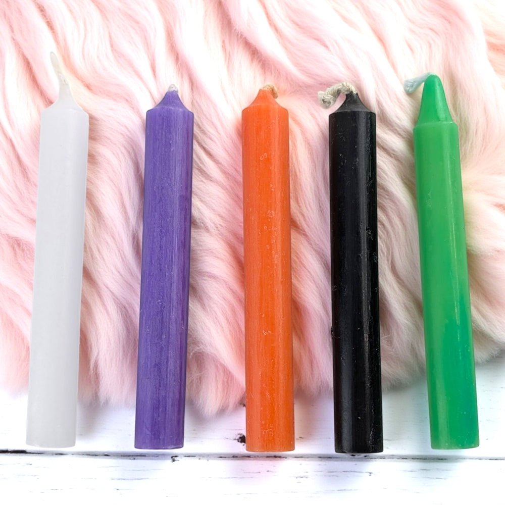 Five colorful candles on a textured pink surface available at zen collection spiritual store in barrie