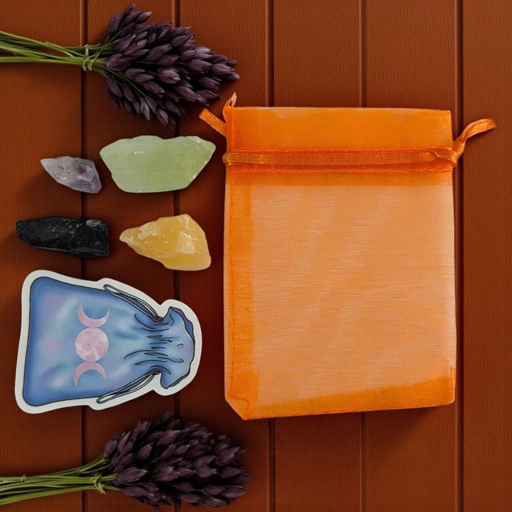 Orange drawstring bag with crystals and a sticker on a wooden surface, witch's crystal set available at zen collection metaphysical store