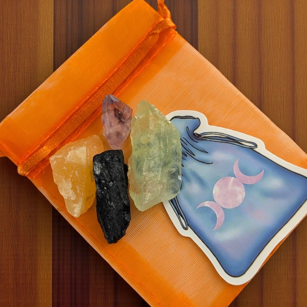 Orange drawstring bag with crystals and a tarot card on a wooden surface witch's crystal set available at zen collection metaphysical store in barrie