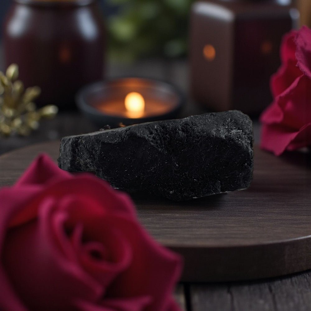 Root Chakra Crystal Black Tourmaline on a wooden surface with red roses and a lit candle in the background. available at zen collection barrie crystal store