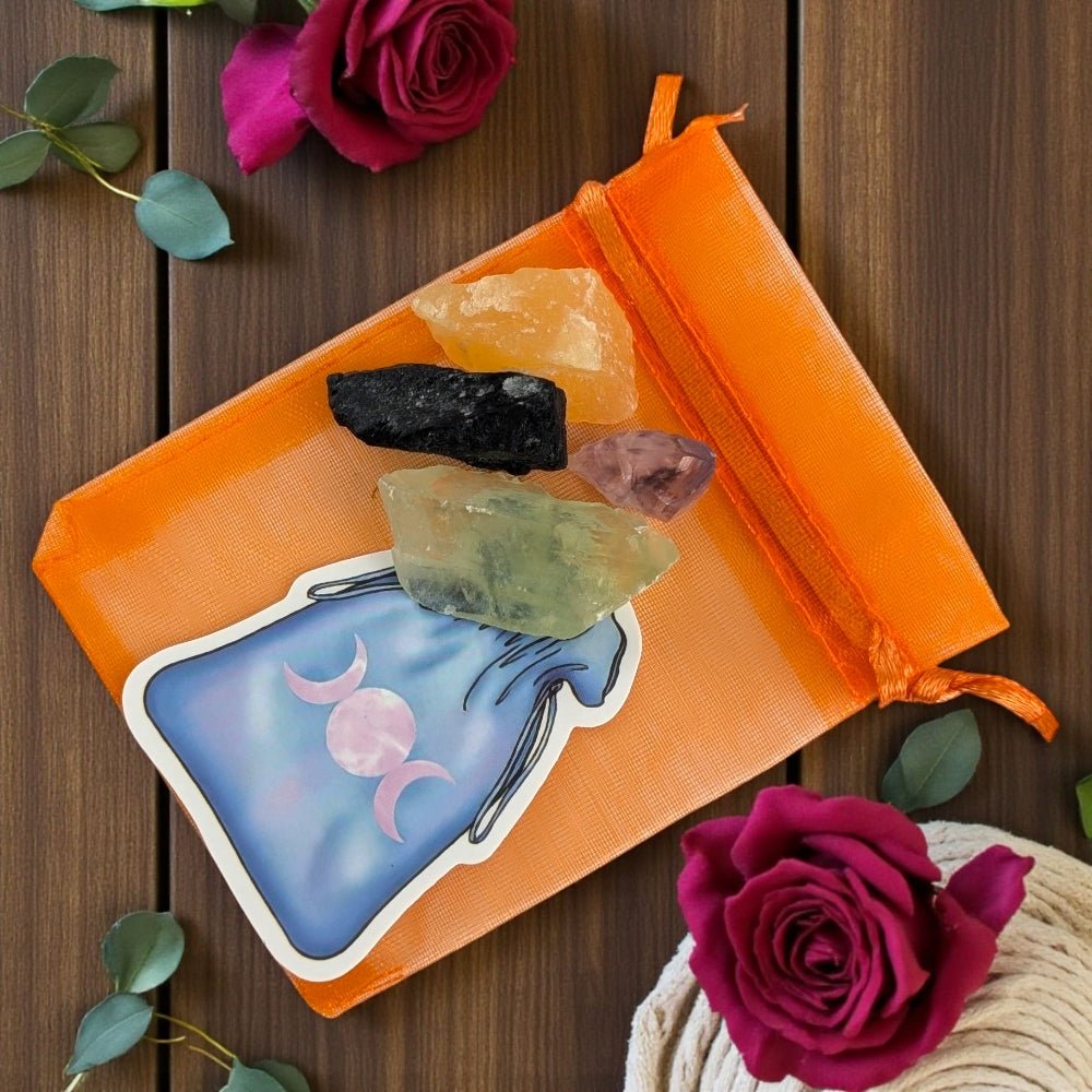 Orange drawstring bag with crystals on a wooden surface with roses. witch's crystal set available at zen collection Barrie crystal stores