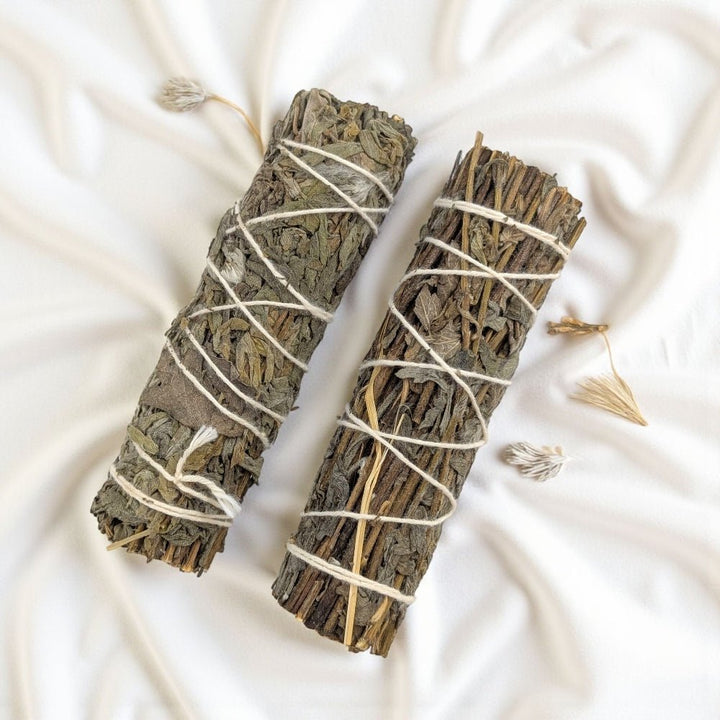 Two mugwort smudge sticks tied with white string on a light fabric background available at Zen Collection Barrie Crystal Store