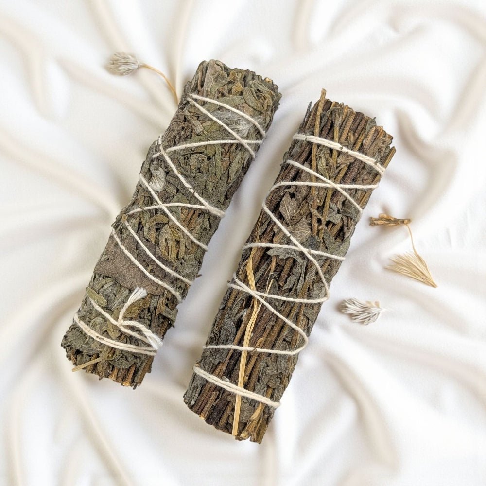 Two mugwort smudge sticks tied with white string on a light fabric background available at Zen Collection Barrie Crystal Store