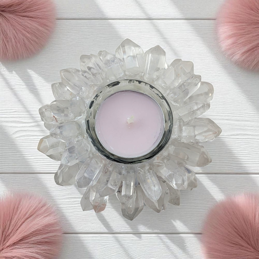 Clear Quartz Crystal candle holder with a pink candle on a white surface with pink fluffy objects around